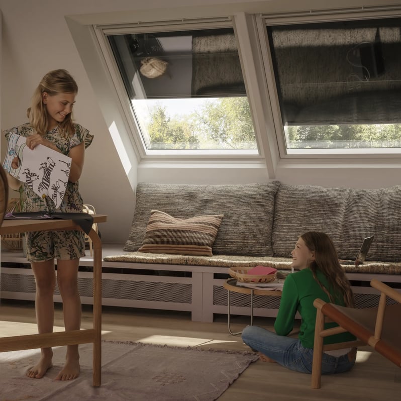 Wnętrze poddasza z oknami dachowymi i roletami VELUX